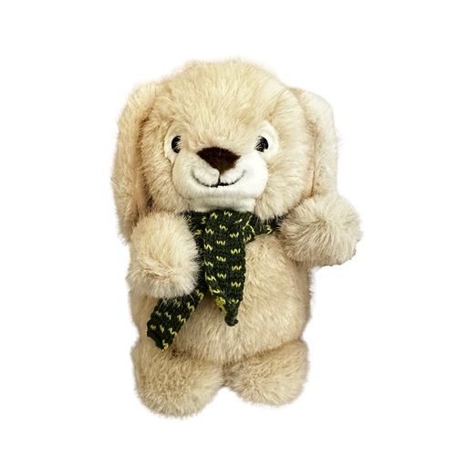 A plush dog toy shaped like a rabbit. It's "standing" upright and made with cream coloured plushy fabric. Its paws are like little balls and its ears are long and hanging down against the side of its head. It has a black nose and eyes and a smiling mouth stitched on with black thread. It's wearing a dark green knitted scarf with lighter green flecks in the pattern.