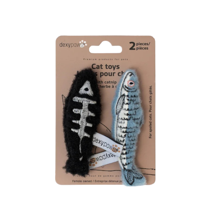 Set of two fish-shaped catnip toys on a brown cardboard card. The one on the left is black with a white skeleton stitched into it. The one on the right's scales and fins are lightly outlined in black. It's light blue with a white underside, and it has wide round eyes outlined in pink.
