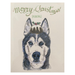 A line and water colour painting of a forward facing husky's head. It's grey with a white face and blue eyes. It has a Christmas pudding on its head between its ears. The pudding is brown and dome shaped, and it has white icing dripping down its side. Its top is decorated with holly leaves and berries. Across the top of the card it says "Merry Christmas" in playful cursive writing, with "(pudding)" in smaller all caps printed text underneath.
